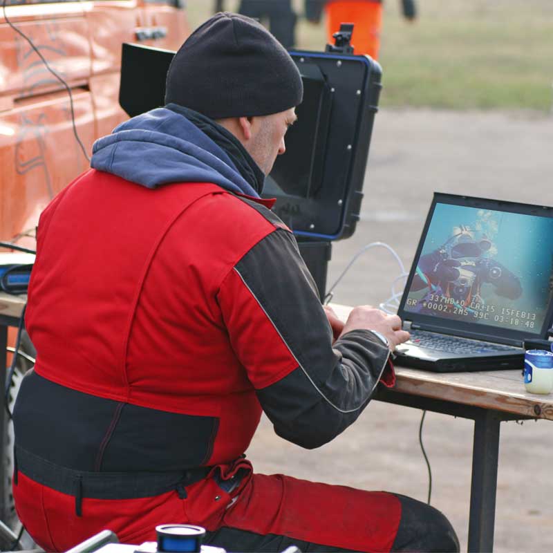 Zwei Berufstaucher kommunizieren via Tauchroboter (ROV) bei einer Anlageninspektion